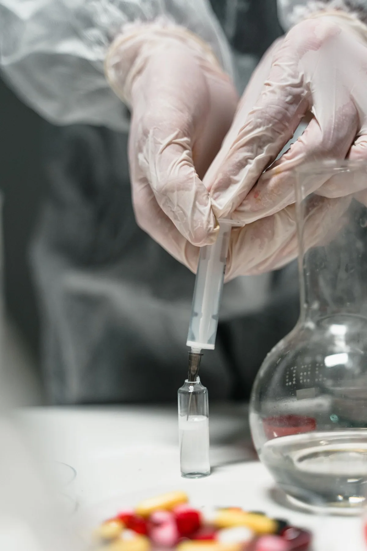 Illustrative medical stock photo of gloved hands using a syringe and glass vial