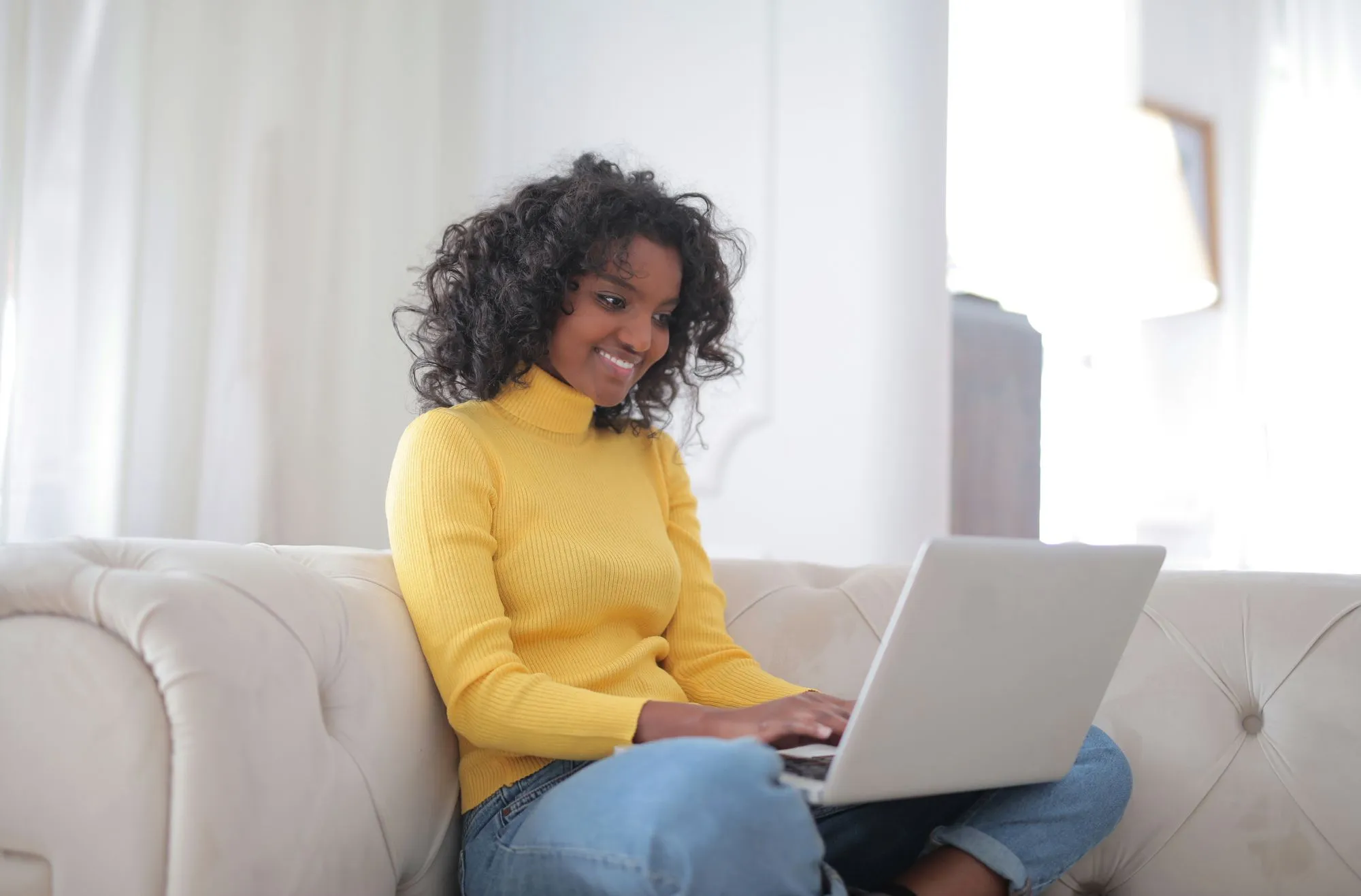 Smiling woman using a laptop on a sofa